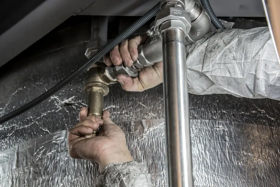 Hands using tools on heating-system piping